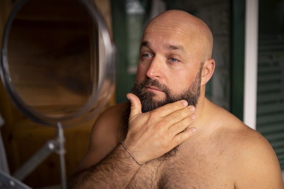 Muškarac sa bradom i obrijanom glavom nakon nege kremom.